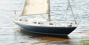 Kumlu kıyıya demirli mavi şalopeli yat (kumsalda otlarla kaplanmış). İsveç 'te, Avrupa' da. Doğa, yaz tatilleri, eğlence, gezi, spor, ulaşım. Hava görünümü