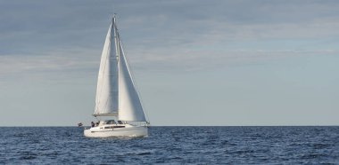 Baltık Denizi 'nde yelkenli bir yat. Gün batımı. Fırtınadan sonra dramatik bir gökyüzü, yumuşak güneş ışığı. Ulaşım, seyahat, seyahat, yat yarışı, spor, eğlence, eğlence, eğlence, yaşam tarzı, aile.