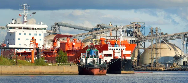 貨物港ターミナルに停泊する大型タンカーや小型船 背景にミネラル肥料の貯蔵とクレーン 貨物輸送 燃料および発電 — ストック写真