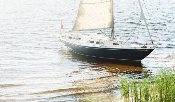 Kumlu kıyıya demirli mavi şalopeli yat (kumsalda otlarla kaplanmış). İsveç 'te, Avrupa' da. Doğa, yaz tatilleri, eğlence, gezi, spor, ulaşım. Hava görünümü
