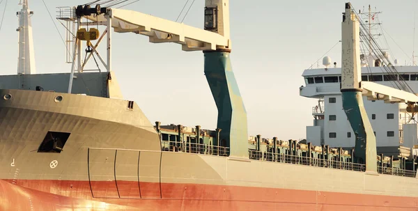 Büyük vinç gemisi (genel yük, 146 metre uzunluğunda) gün batımında açık denizde yol alır. Altın güneş ışığı. Yük taşımacılığı, lojistik, küresel iletişim, ekonomi, sanayi, dünya çapında taşımacılık