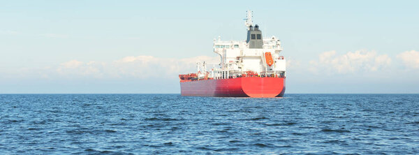 Large red cargo ship (oil chemical tanker, 184  meters length) sailing in the Baltic sea. Freight transportation, logistics, global communications, economy, industry, supply, environment
