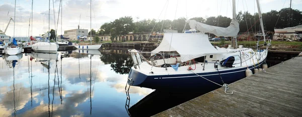 日落时 蓝色的小船停泊在游艇船坞的码头上 戏剧化的天空 闪耀的金色云彩 港口服务 — 图库照片