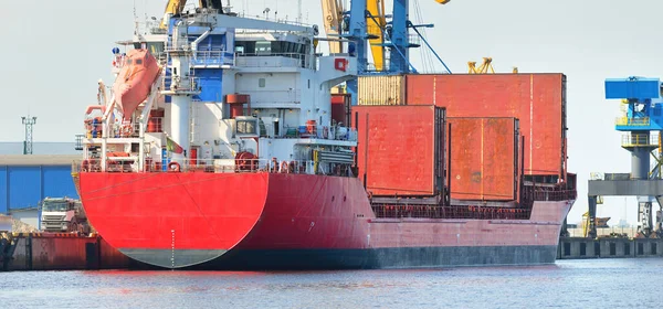 Liman terminalinde büyük bir kargo gemisi yükleniyor, arka planda vinçler var. Yük taşımacılığı, lojistik, küresel iletişim, ekonomi, ticaret, sanayi, özel ekipman