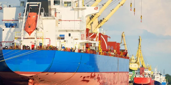Büyük kargo gemisi (toplu taşıyıcı, 187 metre uzunluğunda) iskele terminalinde yükleme, arka planda vinçler. Yük taşımacılığı, lojistik, küresel iletişim, ekonomi, ticaret, sanayi