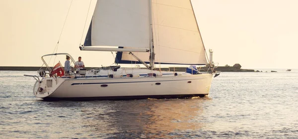 Günbatımında Baltık Denizi 'nde yelkenli yelkenli yelkenli. Fırtınadan sonra gökyüzü açık, altın güneş ışığı. Ulaşım, seyahat, gezi, spor, eğlence, boş zaman aktivitesi, yarış, yelkenli yarışı