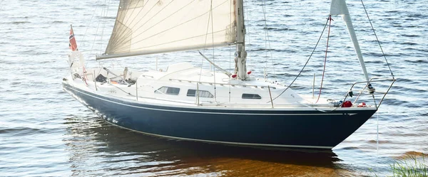 Kumlu kıyıya demirli mavi şalopeli yat (kumsalda otlarla kaplanmış). İsveç 'te, Avrupa' da. Doğa, yaz tatilleri, eğlence, gezi, spor, ulaşım. Hava görünümü