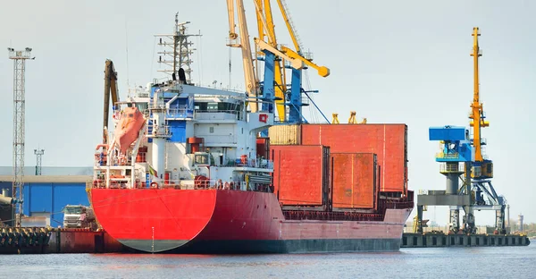 Liman terminalinde büyük bir kargo gemisi yükleniyor, arka planda vinçler var. Yük taşımacılığı, lojistik, küresel iletişim, ekonomi, ticaret, sanayi, özel ekipman