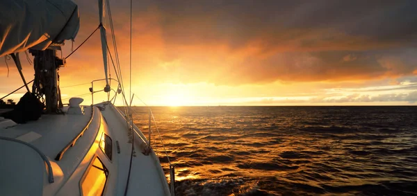 日落时 白色游艇在开阔的海面上航行 从甲板到船头的景色 史诗般的云雾 暴风雨过后 天空戏剧化 金光闪闪 休闲活动 — 图库照片