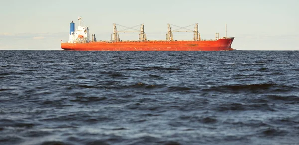 Büyük kırmızı bir yük gemisi (179 metre uzunluğunda) açık bir Baltık Denizi 'nde yüzüyor. Dramatik bir gökyüzü. Yük taşımacılığı, denizcilik gemisi, lojistik, küresel iletişim, ekonomi, iş dünyası, sanayi