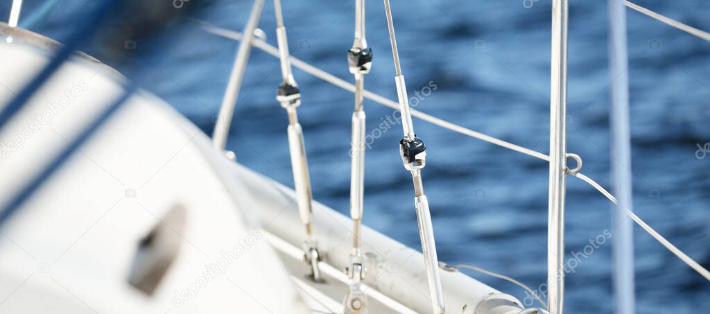 White sloop rigged yacht sailing in the Baltic sea at sunset. View from a cockpit. Boat side railing close-up. Transportation, travel, cruise, sport, recreation, leisure activity, regatta