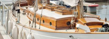 Yeni bir yat limanındaki iskeleye demirlenmiş pahalı bir retro yelkenli (ketch). Tahta meşe güvertesi, zarif detaylar. Ulaşım, denizcilik gemisi, tatiller, turizm, seyahat, yat yarışı, dinlenme