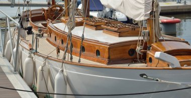 Yeni bir yat limanındaki iskeleye demirlenmiş pahalı bir retro yelkenli (ketch). Tahta meşe güvertesi, zarif detaylar. Ulaşım, denizcilik gemisi, tatiller, turizm, seyahat, yat yarışı, dinlenme