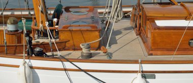 Yeni bir yat limanındaki iskeleye demirlenmiş pahalı bir retro yelkenli (ketch). Tahta meşe güvertesi, zarif detaylar. Ulaşım, denizcilik gemisi, tatiller, turizm, seyahat, yat yarışı, dinlenme