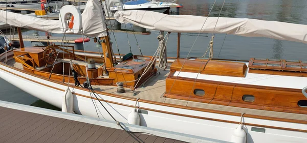 Yeni bir yat limanındaki iskeleye demirlenmiş pahalı bir retro yelkenli (ketch). Tahta meşe güvertesi, zarif detaylar. Ulaşım, denizcilik gemisi, tatiller, turizm, seyahat, yat yarışı, dinlenme