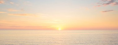 Mavi gökyüzünün altında, parlak pembe ve altın renkli günbatımı bulutlarıyla Baltık deniz kıyısında. Kaya kıyısı, dalgalar. Idyllic deniz manzarası. - Letonya. Doğa, çevre koruma, eko-turizm. Resim gibi bir manzara.