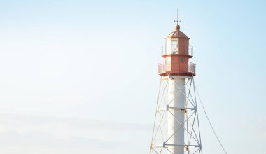 Deniz fenerine karşı açık mavi gün batımı gökyüzü. Hafif ışık, altın saat. Letonya 'nın Pape köyü. Idyllic manzara. İnşaat, sahil güvenlik, yön bulma, umut ve barışın sembolü. Panoramik görünüm, boşluğu kopyala