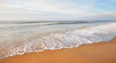 Gün batımında Baltık kıyıları (kum tepeleri). Yumuşak güneş ışığı, parlayan bulutlar, dalgalar ve su fışkıran berrak gökyüzü. Idyllic deniz manzarası. Liepaja, Letonya, Avrupa. Sıcak kış havası, iklim değişikliği, doğa
