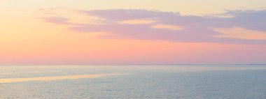 Gün batımında Baltık Denizi. Dramatik gökyüzü, mavi ve pembe parlayan bulutlar, yumuşak altın güneş ışığı, gece yarısı güneşi. Deniz manzarası, bulut manzarası, doğa. Panoramik görünüm