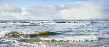 Kumlu sahilden Baltık denizinin panoramik görüntüsü (kum tepeleri). Parlayan bulutları, güneş ışınları olan dramatik bir gökyüzü. Dalgalar, su sıçramaları. Idyllic deniz manzarası. Sıcak kış havası, iklim değişikliği, doğa. Danimarka