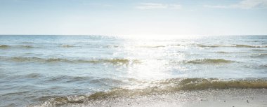 Baltık deniz kıyısı. Açık mavi gökyüzü. Yumuşak güneş ışığı. Kumsal, kum tepeleri, çakıl taşları. Saf doğa, çevre koruma, ekoloji, eko-turizm, yürüyüş, yaz tatili, dinlenme. Panoramik görünüm