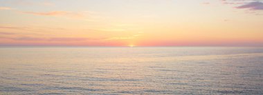 Gün batımında Baltık Denizi. Dramatik gökyüzü, mavi ve pembe parlayan bulutlar, yumuşak altın güneş ışığı, gece yarısı güneşi. Deniz manzarası, bulut manzarası, doğa. Panoramik görünüm