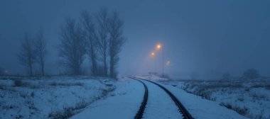 Geceleri karla kaplı demiryolu aydınlanıyor. Atmosferik kış manzarası. Gizemli mavi ışık. Ulaşım. Güvenlik, tehlike kavramları