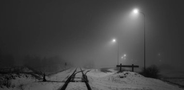 Geceleri karla kaplı demiryolu aydınlanıyor. Atmosferik kış manzarası. Siyah beyaz görüntü. Boşluk, sessizlik, yalnızlık kavramları.