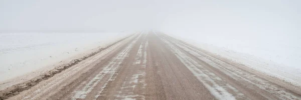 吹雪の中で雪に覆われたフィールドを介してカントリーロード 濃い白い霧 背景には孤独な木 大気の冬の風景 氷の砂漠 — ストック写真
