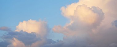 Açık mavi gökyüzü. Pembe ve altın rengi sirrus ve kümülüs bulutları fırtına üstüne, yumuşak güneş ışığı. Dramatik gün batımı bulutları. Meteoroloji, cennet, barış, grafik kaynakları, pitoresk panoramik manzara