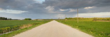 Fırtınadan sonra tarladan geçen boş köy yolu. Arabadan bir manzara. Idyllic kırsal kesim. Renkli, parlayan günbatımı bulutları. Ulaşım, yolculuk, özgürlük, seyahat tutkusu, uzak yerler kavramları.