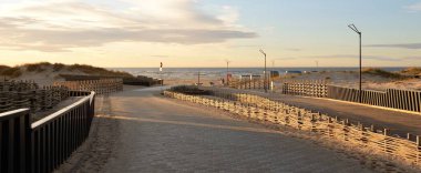 Gün batımında Baltık kıyısı. Yürüyüş ve eğlence alanı. Yumuşak güneş ışığı. Doğa, çevre, yerel seyahat, eko turizm