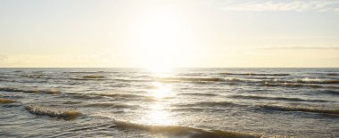 Kumlu bir sahilden (kum tepeleri) Baltık denizinin panoramik görüntüsü. Parlayan bulutlarla, dalgalarla ve su sıçramalarıyla berrak bir gökyüzü. Idyllic deniz manzarası. Sıcak kış havası, iklim değişikliği, doğa
