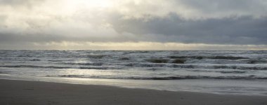 Fırtınadan sonra Baltık Denizi. Yumuşak günbatımı ışığı, çarpıcı parlayan bulutlar. Deniz manzarası, bulutlar, doğa. Panoramik manzara. Ekoloji, iklim değişikliği, hava durumu