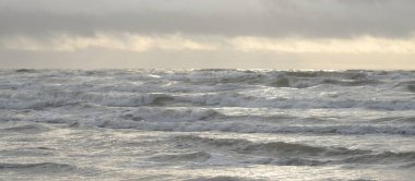 Fırtınadan sonra Baltık Denizi. Yumuşak günbatımı ışığı, çarpıcı parlayan bulutlar. Deniz manzarası, bulutlar, doğa. Panoramik manzara. Ekoloji, iklim değişikliği, hava durumu