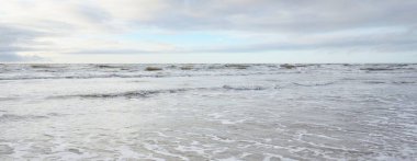 Fırtınadan sonra Baltık Denizi. Yumuşak günbatımı ışığı, çarpıcı parlayan bulutlar. Deniz manzarası, bulutlar, doğa. Panoramik manzara. Ekoloji, iklim değişikliği, hava durumu