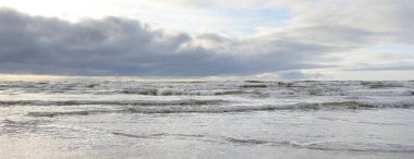 Fırtınadan sonra Baltık Denizi. Yumuşak günbatımı ışığı, çarpıcı parlayan bulutlar. Deniz manzarası, bulutlar, doğa. Panoramik manzara. Ekoloji, iklim değişikliği, hava durumu