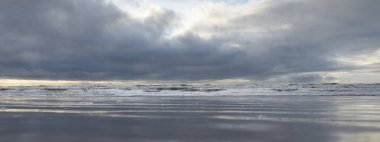 Fırtınadan sonra Baltık Denizi. Yumuşak günbatımı ışığı, çarpıcı parlayan bulutlar. Deniz manzarası, bulutlar, doğa. Sudaki yansımalar. Panoramik manzara. Ekoloji, iklim değişikliği, hava durumu
