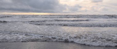 Fırtınadan sonra Baltık Denizi. Yumuşak günbatımı ışığı, çarpıcı parlayan bulutlar. Deniz manzarası, bulutlar, doğa. Sudaki yansımalar. Panoramik manzara. Ekoloji, iklim değişikliği, hava durumu