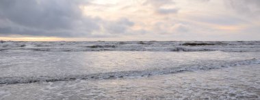 Fırtınadan sonra Baltık Denizi. Yumuşak günbatımı ışığı, çarpıcı parlayan bulutlar. Deniz manzarası, bulutlar, doğa. Sudaki yansımalar. Panoramik manzara. Ekoloji, iklim değişikliği, hava durumu