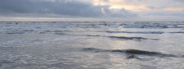 Fırtınadan sonra Baltık Denizi. Yumuşak günbatımı ışığı, çarpıcı parlayan bulutlar. Deniz manzarası, bulutlar, doğa. Panoramik manzara. Ekoloji, iklim değişikliği, hava durumu