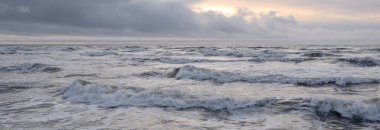 Fırtınadan sonra Baltık Denizi. Yumuşak günbatımı ışığı, çarpıcı parlayan bulutlar. Deniz manzarası, bulutlar, doğa. Panoramik manzara. Ekoloji, iklim değişikliği, hava durumu