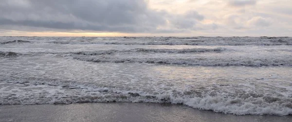 Fırtınadan sonra Baltık Denizi. Yumuşak günbatımı ışığı, çarpıcı parlayan bulutlar. Deniz manzarası, bulutlar, doğa. Sudaki yansımalar. Panoramik manzara. Ekoloji, iklim değişikliği, hava durumu
