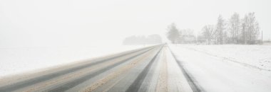 Karla kaplı orman ve kırsal alanda boş otoyol (asfalt yol). Kar fırtınası, kar yağışı. Avrupa. Doğa, Noel tatilleri, uzak yerler, kış lastikleri, tehlikeli sürüş konsepti