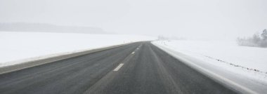 Karla kaplı orman ve kırsal alanda boş otoyol (asfalt yol). Kar fırtınası, kar yağışı. Avrupa. Doğa, Noel tatilleri, uzak yerler, kış lastikleri, tehlikeli sürüş konsepti