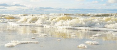 Kumlu bir sahilden (kum tepeleri) Baltık denizinin panoramik görüntüsü. Parlayan bulutlarla, dalgalarla ve su sıçramalarıyla berrak bir gökyüzü. Idyllic deniz manzarası. Sıcak kış havası, iklim değişikliği, doğa