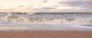 Gün batımında Baltık kıyıları (kum tepeleri). Yumuşak güneş ışığı, parlayan bulutlar, dalgalar ve su fışkıran berrak gökyüzü. Idyllic deniz manzarası. Liepaja, Letonya, Avrupa. Sıcak kış havası, iklim değişikliği, doğa