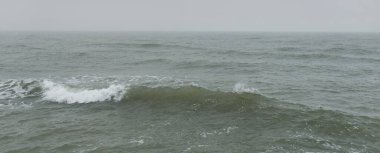 Sis içindeki Baltık Denizi. Dalgalar, su sıçratma, fırtına. Doğal dokular. Resimli panoramik monokrom manzarası, deniz manzarası. Doğa, çevre, sert hava, tehlike