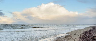 Gün batımında Baltık kıyısı. Kumsal, kum tepeleri. Dramatik gökyüzü akan bulutlar. Yumuşak güneş ışığı. Doğa, hava, çevre, eko turizm