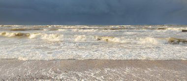 Fırtınadan sonra Baltık kıyıları (kum tepeleri, plaj). Dramatik gökyüzü, parlayan bulutlar. Resimli panoramik manzara. Doğa, çevre, ekoloji, eko-turizm, yürüyüş, keşif kavramları